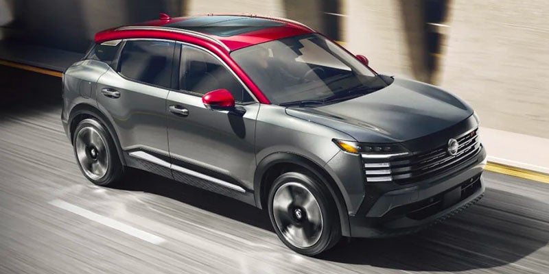 Gray compact SUV with a red roof, mirror caps, and accents, driving on a blurred road.