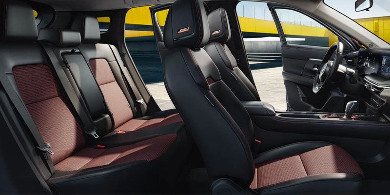 The interior of a car with black leather seats featuring red checkered pattern inserts and red stitching.
