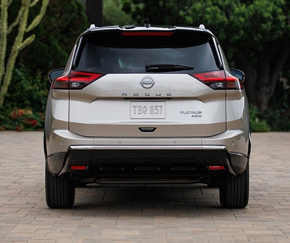 Rear view of a silver Nissan Rogue Platinum SUV parked on a paved surface.